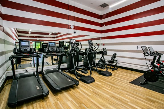 a gym with cardio equipment and a red and white wall