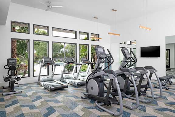 A gym with treadmills, exercise bikes, and a television.