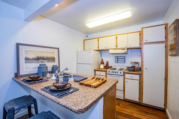 A kitchen with a table set for two and a painting on the wall.