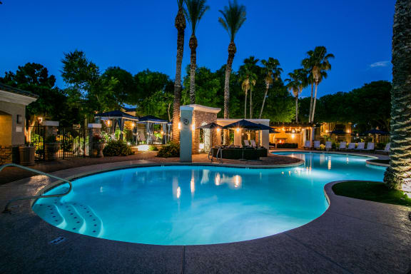 a swimming pool at night at a resort with palm trees