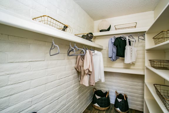 a walk in closet with shelves and hooks and shoes on the wall