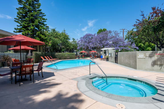 a swimming pool and patio with tables and umbrellas at the resort style pool