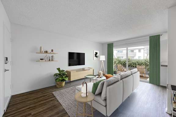 A living room with a grey couch, a small table, and a television.