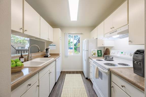 A kitchen with white appliances and cabinets.