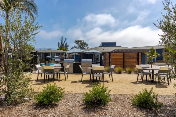 a bbq area with tables and chairs and a building in the background