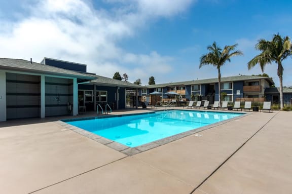 a swimming pool in front of a building with palm trees