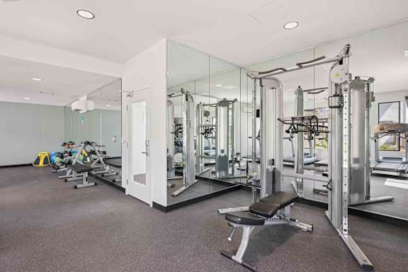 A gym with a variety of equipment including free weights, a smith machine, and treadmills.