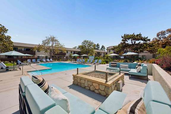 A pool area with a hot tub and lounge chairs.