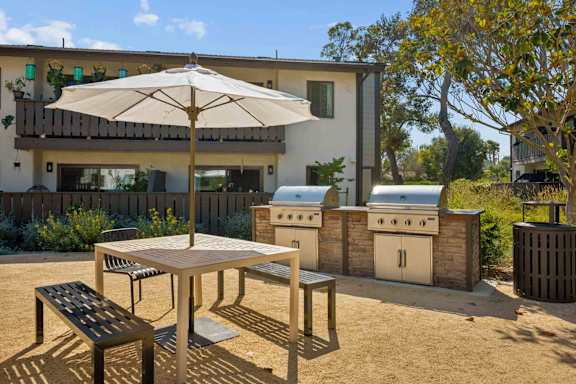 A patio with a table, chairs and an umbrella.