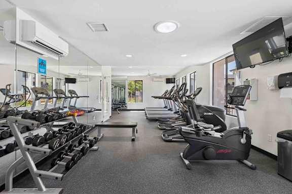 A gym with a variety of equipment including treadmills, stationary bikes, and weight machines.