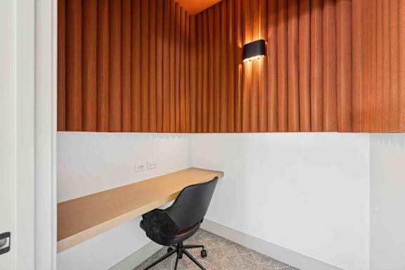 A black chair is in front of a wooden wall.