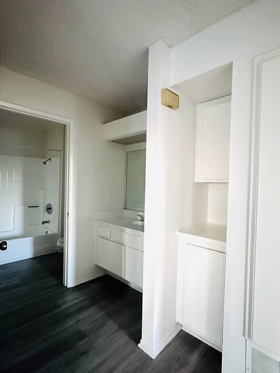 A white bathroom with a black floor and a white door.
