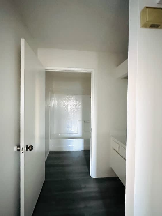 A hallway with a black floor and white walls.