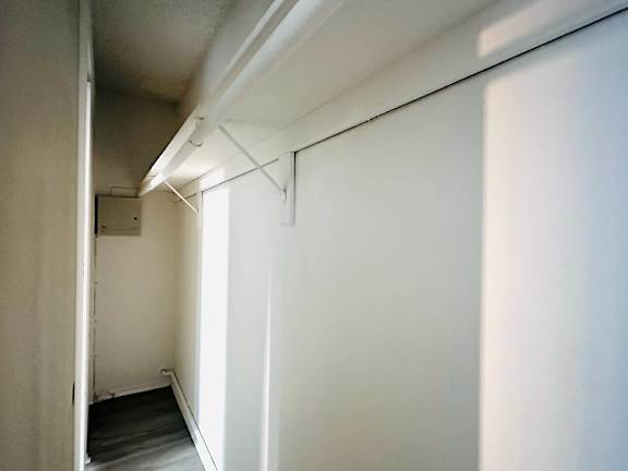 A long white hallway with a door on the left.