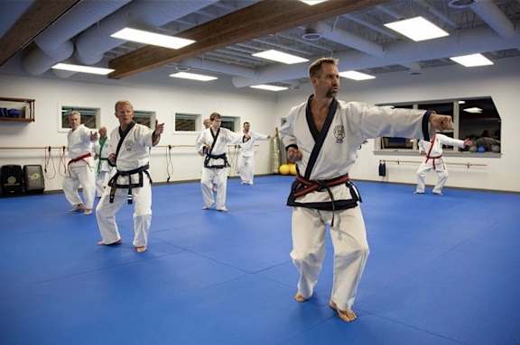 A group of people practicing karate in a blue-carpeted room.