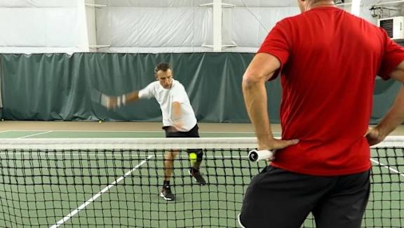 A man in a red shirt is standing on a tennis court.