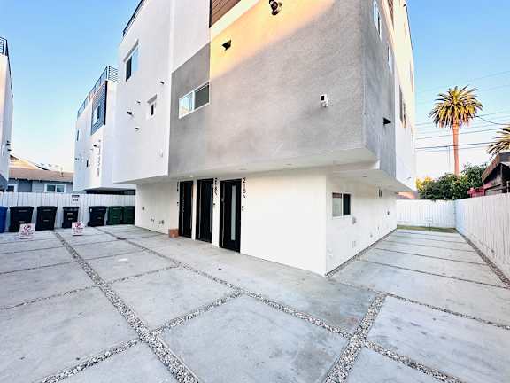 A modern building with a white exterior and a concrete courtyard.