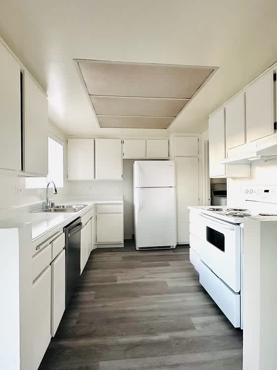 A white kitchen with a refrigerator, oven, and sink.