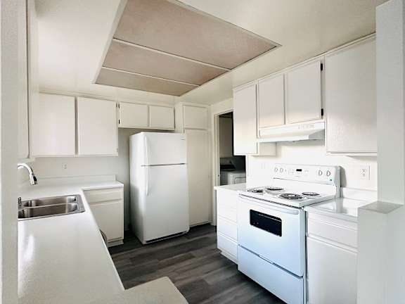 A white kitchen with a sink, refrigerator, and stove at Lido Apartments - 101-197 N Ridgeway, Anaheim, CA