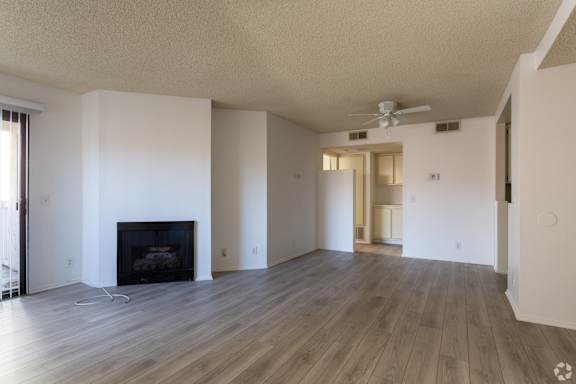 A living room with a fireplace and a fan on the ceiling at Lido Apartments - 101-197 N Ridgeway, Anaheim, CA