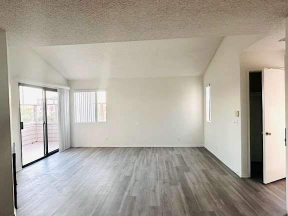 A room with a sliding glass door and wood flooring.