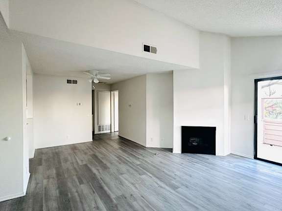 A spacious living room with a fireplace and a ceiling fan.