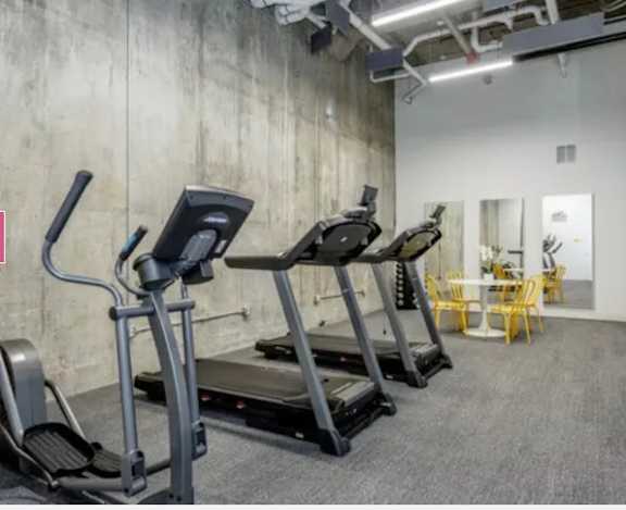 A gym with treadmills and a dining table.