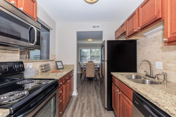 a kitchen with granite counter tops and black appliances at Sawgrass Apartments, Charleston, SC