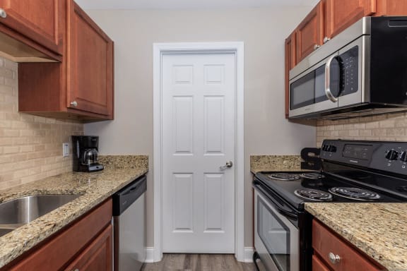 a kitchen with granite counter tops and a white door at Sawgrass Apartments, South Carolina, 29412