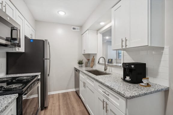 a kitchen with white cabinets and granite counter tops and a stainless steel refrigerator at Lake Johnson Mews, North Carolina, 27606