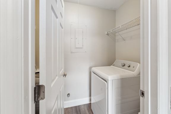 A white washing machine sits in a small laundry room.