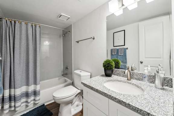 A bathroom with a white toilet, sink, and shower. at Linkhorn Bay Apartments, Virginia Beach, VA