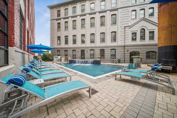 A pool with blue loungers and a waterfall feature at The Locks, Virginia, 23219
