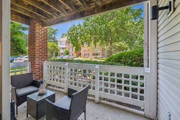 A patio with a white fence and a brick pillar at The Timbers Apartments, Richmond