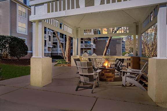 a covered patio with a fire pit and rocking chairs at Beacon Ridge Apartments, PRG Real Estate Management, Greenville, SC 29615