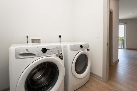 Two white front load washing machines in a laundry room at The Waterford At Rocketts Landing Apartments, PRG Real Estate, Richmond, VA
