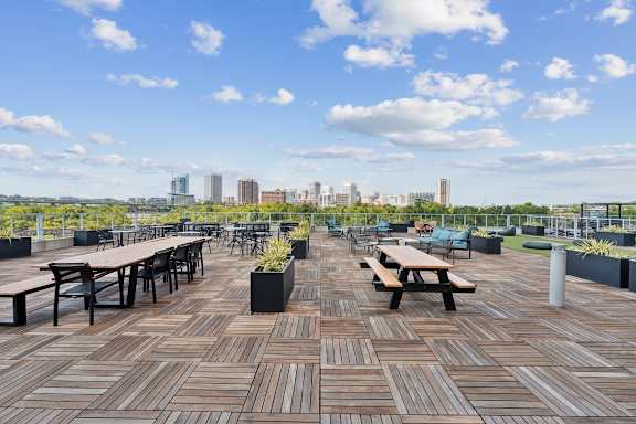 A wooden deck with benches and tables overlooking a city skyline. at South Falls Tower Apartments, Richmond, Virginia