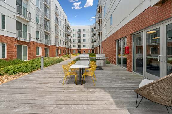 A patio with a table and chairs is surrounded by apartment buildings at The Waterford At Rocketts Landing Apartments, PRG Real Estate, Richmond, VA