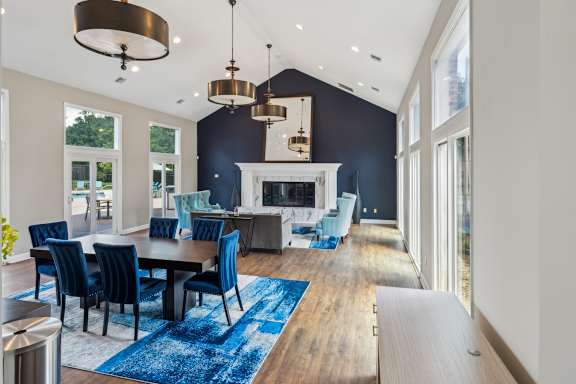 A modern dining room with a fireplace and blue chairs. at The Timbers Apartments, Richmond, Virginia