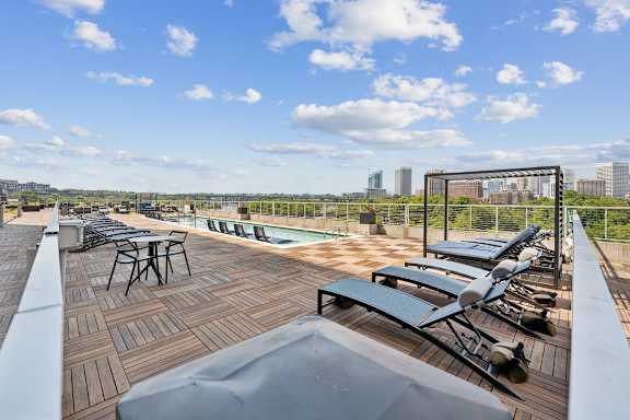 A rooftop patio with a table and chairs overlooking a city skyline. at South Falls Tower Apartments, Richmond 23224