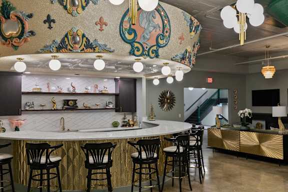 A bar with a gold and black counter and chairs.