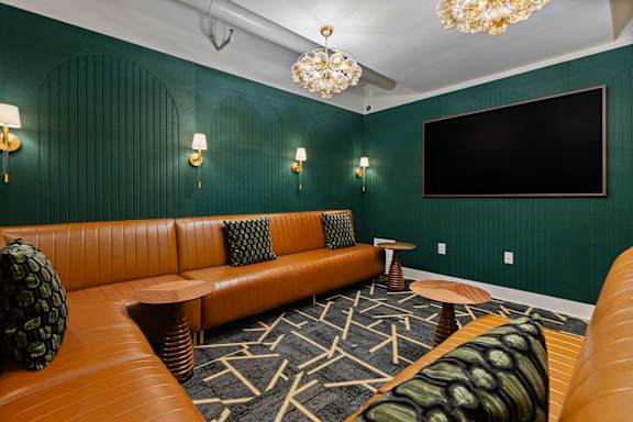 A room with a green wall and a brown leather couch.