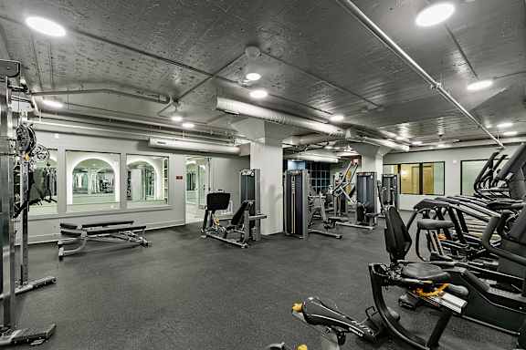A gym with a variety of equipment including treadmills, weights, and exercise machines.