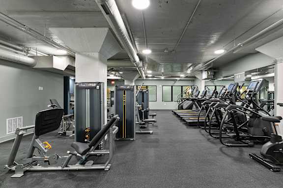 A gym with a variety of equipment including treadmills, stationary bikes, and weight machines.
