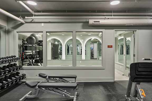 A gym with a mirrored wall and a variety of equipment.