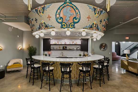A bar area with a white counter and black stools.