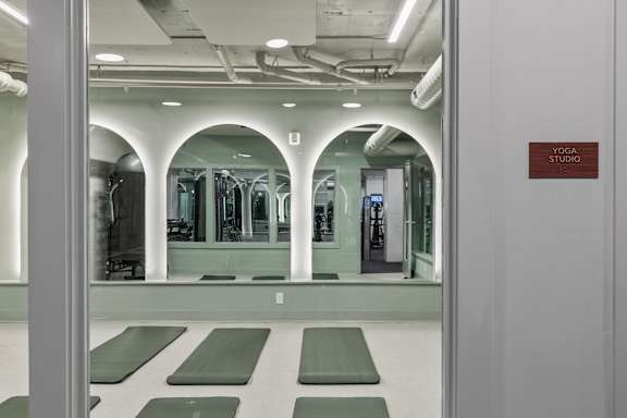 A yoga studio with green mats and mirrors on the wall.