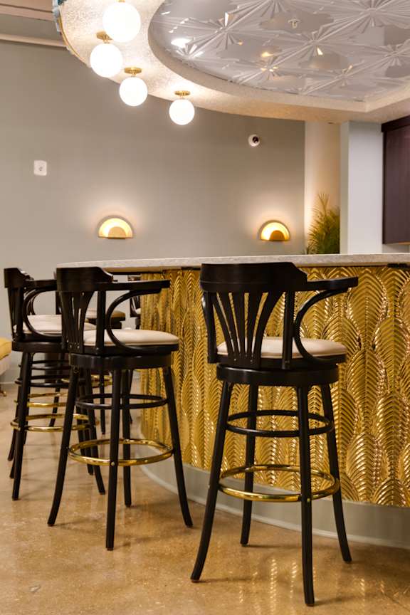A set of four black bar stools with gold accents.