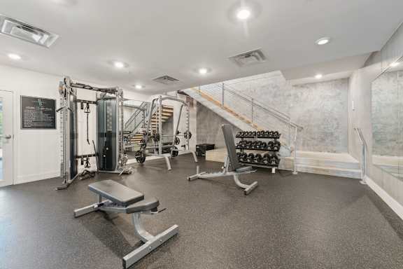 A gym with a variety of equipment including a bench, weights, and a squat rack. at South Falls Tower Apartments, Richmond