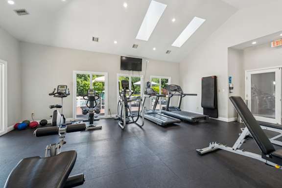 A spacious gym with a variety of equipment including treadmills, exercise bikes, and weight machines at The Timbers Apartments, Richmond 23235